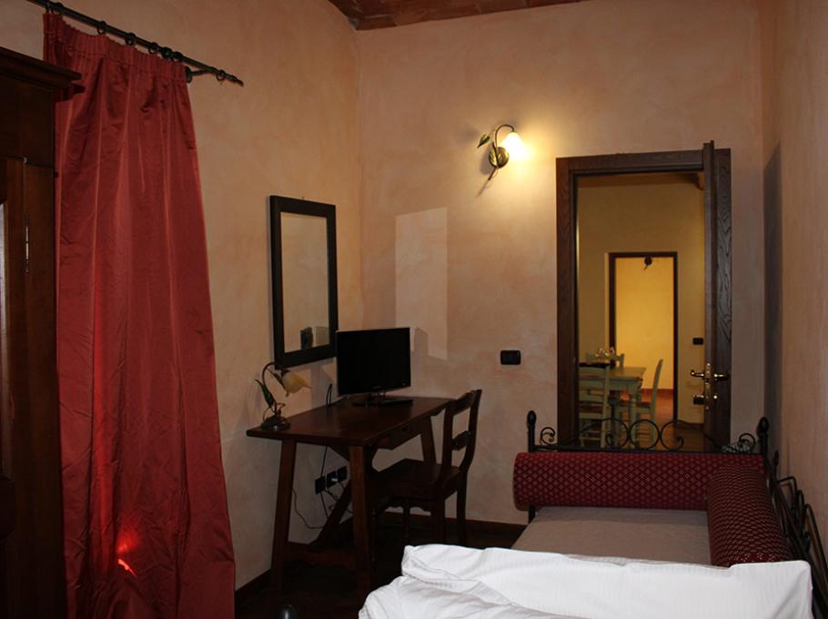 Camera accogliente con luce soffusa, tende rosse e arredi in legno.