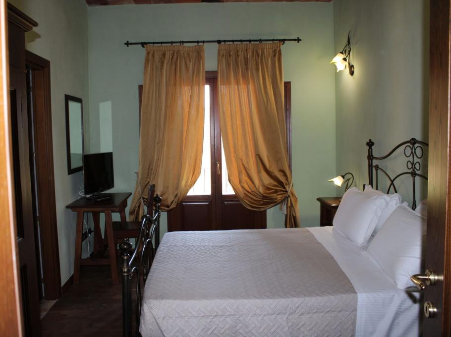 Camera accogliente con letto matrimoniale, tende dorate e luci soffuse.