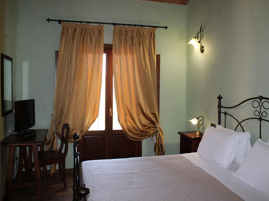Camera accogliente con letto elegante, tende dorate e luce soffusa.