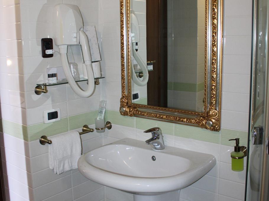 Bagno elegante con specchio dorato, asciugacapelli e lavandino moderno.