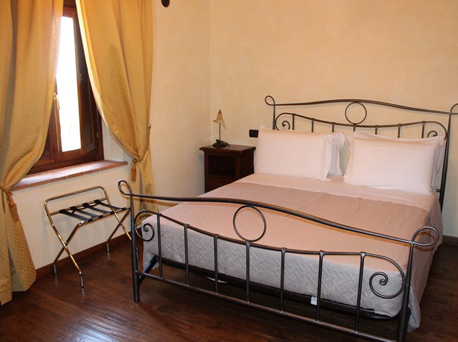 Camera da letto con letto matrimoniale, lampada da comodino e tende marroni.