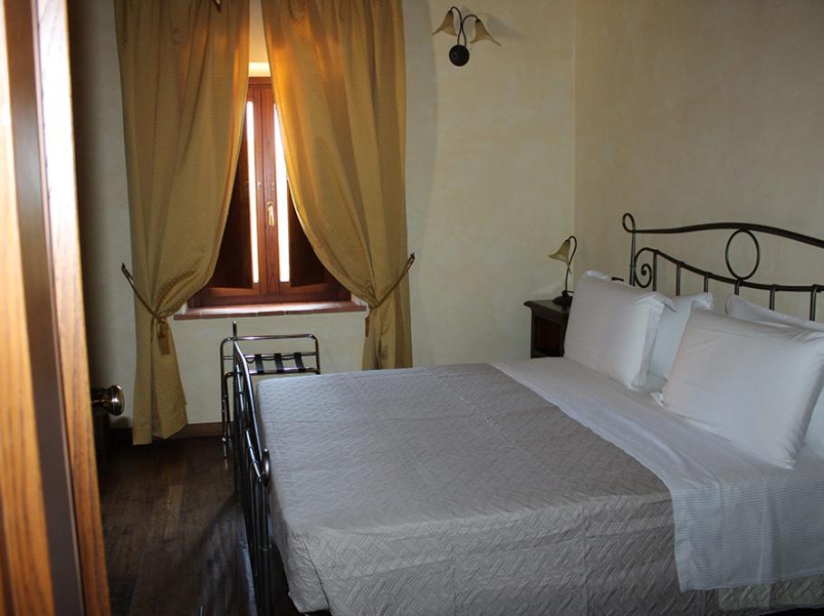 Camera accogliente con letto matrimoniale, tende calde e luce soffusa.