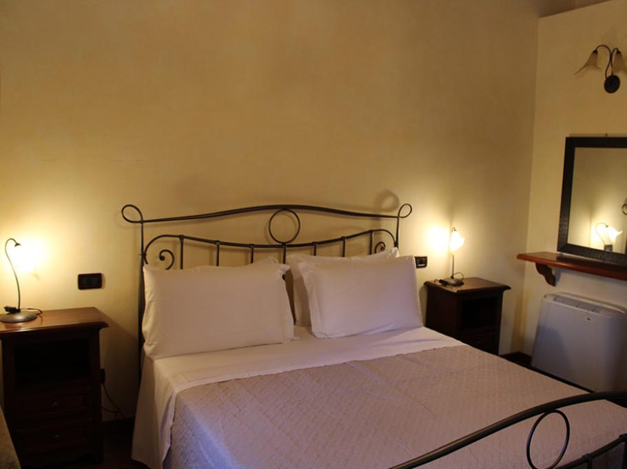 Camera accogliente con letto matrimoniale, illuminazione calda e arredo classico.