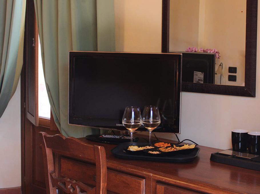 Camera accogliente con vino, snack e TV su un tavolo di legno.