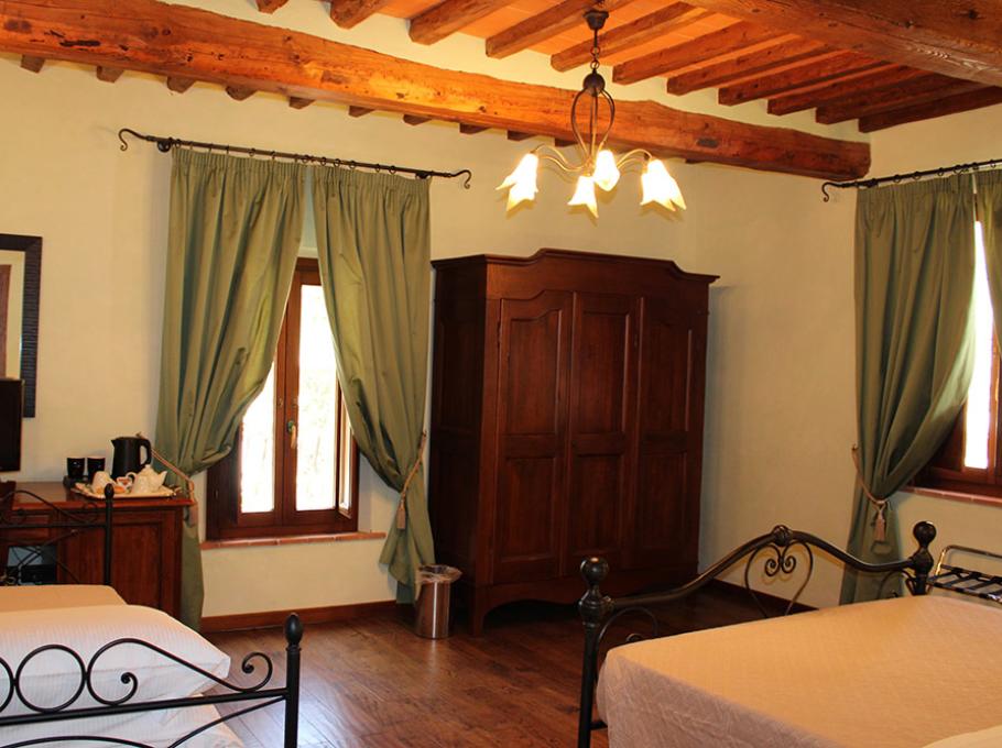 Camera da letto accogliente con letto in ferro battuto e travi a vista.